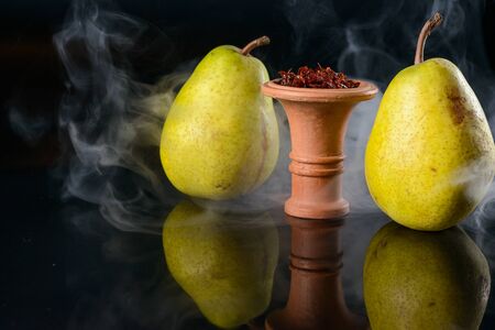 Fragrant pear tobacco for hookah in bowl on black glass backgroundの写真素材