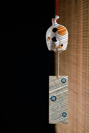 Cat shaped ceramic bell on bamboo jalousie background