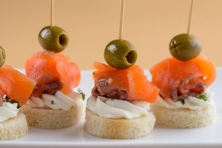 Canape with red fish, olives and cream cheese on white plateの写真素材