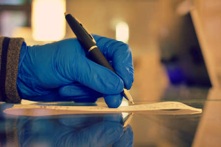 a person signing the bill with surgical gloves while Corona Virus