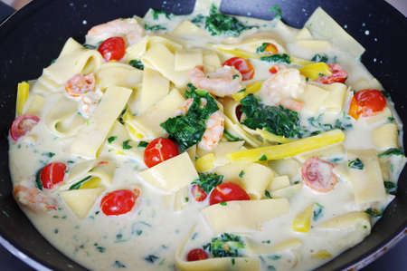 Pasta with shrimp, tomatoes and spinach.の写真素材