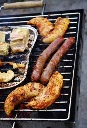 Meat, fish, bread and sausage beeing broiled on the barbecue grill.の写真素材