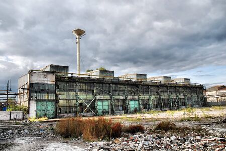 Old shut down factory is overshadowed by dark stormy cloudsの写真素材