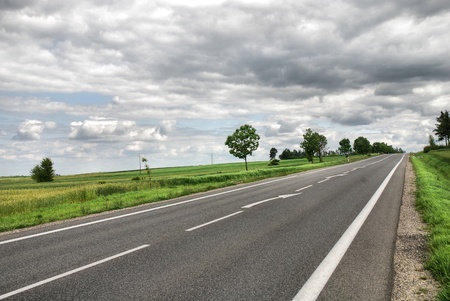 A deserted country road running through some green fields