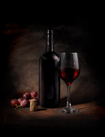 Still life with red wine, glass, dark grapes and cork, against a dark background, in a baroque style, with strong chiaroscuro.の写真素材