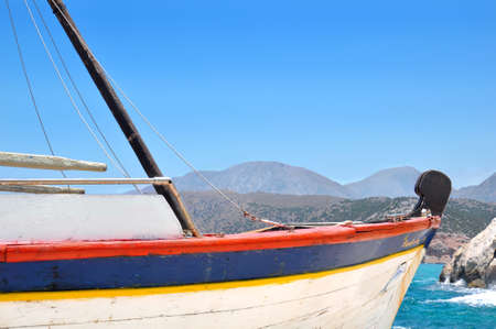 An old sailing boat in a bay, nailing to the rocky shore.の写真素材