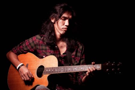 Long hair guy playing guitar acousticの写真素材