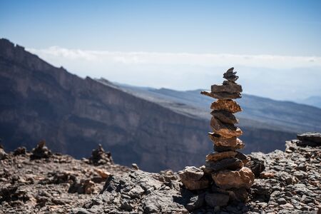 Small grouping of stones with the mountains in the background at the Grand Canyon of Jebel Shams, Omanの写真素材