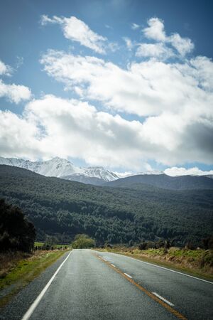 Splendid image of the SH94 road towards Milford Sound surrounded by greenery with snow capped...