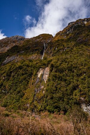 Impressive image of a waterfall on the SH94 road towards Milford Sound taken on a sunny winter day, New Zealandの写真素材