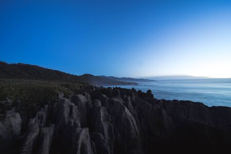 Beautiful panorama of an orange sunset at Pancake Rocks on a sunny winter day in Punakaiki, New...