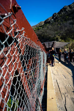 Kawarau Bridge, New Zealand, October 6, 2019: Close-up of the bridge fence with boys in the background preparing to bungee jump with A.J. Hackettのeditorial素材