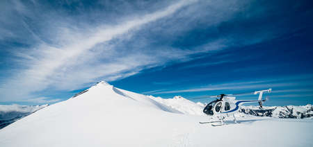 Mount Aspiring, New Zealand, October 6, 2019: Stunning panorama of a helicopter waiting to take off on top of the snowy mountain taken on a sunny dayのeditorial素材