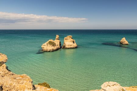 The bay of Torre dell'Orso, with its high cliffs, in Salento, Puglia, Italy. Turquoise sea and blue sky, sunny day in summer. The stacks called the Two Sisters, immersed in the sea.の写真素材
