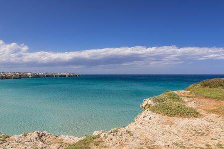 The bay of Torre dell'Orso, with its high cliffs, in Salento, Puglia, Italy. Turquoise sea and blue sky, sunny day in summer. Panorama of the sea on the horizon and houses on the reef.の写真素材