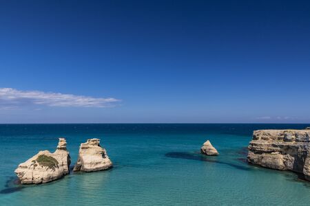 The bay of Torre dell'Orso, with its high cliffs, in Salento, Puglia, Italy. Turquoise sea and blue sky, sunny day in summer. The stacks called the Two Sisters, immersed in the sea.の写真素材