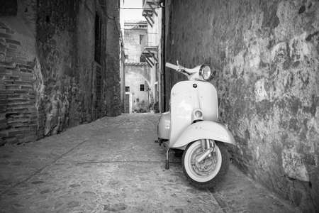 June 30, 2019 - Rome, Lazio, Italy - A white Piaggio Vespa Sprint, parked in an alleyway of an ancient village, in Italy. The scooter symbol of Italian design.のeditorial素材