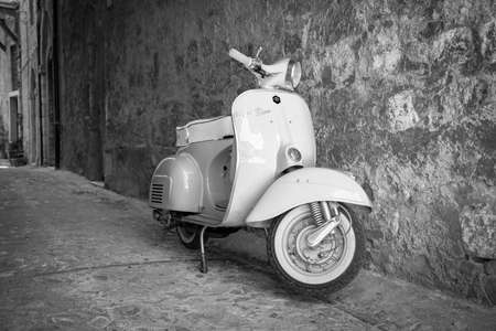 June 30, 2019 - Rome, Lazio, Italy - A white Piaggio Vespa Sprint, parked in an alleyway of an ancient village, in Italy. The scooter symbol of Italian design.のeditorial素材