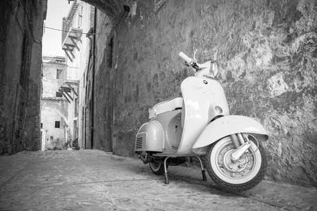 June 30, 2019 - Rome, Lazio, Italy - A white Piaggio Vespa Sprint, parked in an alleyway of an ancient village, in Italy. The scooter symbol of Italian design.のeditorial素材