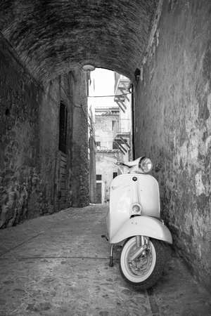June 30, 2019 - Rome, Lazio, Italy - A white Piaggio Vespa Sprint, parked in an alleyway of an ancient village, in Italy. The scooter symbol of Italian design.のeditorial素材