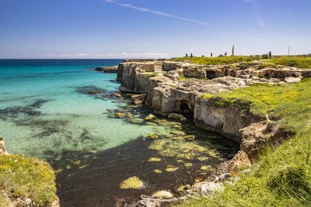 The important archaeological site and tourist resort of Roca Vecchia, in Puglia, Salento, Italy. Turquoise sea, blue sky, rocks, sun, lush vegetation in summer. Basiliane Caves (VIII century)の写真素材