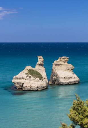 The bay of Torre dell'Orso, with its high cliffs, in Salento, Puglia, Italy. Turquoise sea and blue sky, sunny day in summer. The stacks called the Two Sisters, immersed in the sea.の写真素材