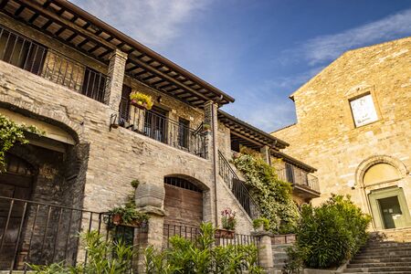 One of the ancient churches of the medieval village of Bevagna. Perugia, Umbria, Italy. Brick and stone houses with flowered balconies.の写真素材