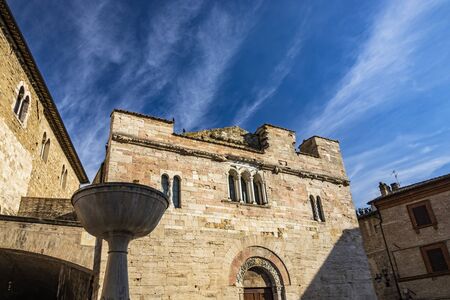 The medieval Palazzo dei Consoli in the village of Bevagna. Brick and stone wall and mullioned windows. The Romanesque Church of San Silvestro. The marble fountain. Perugia, Umbria, Italy.の写真素材