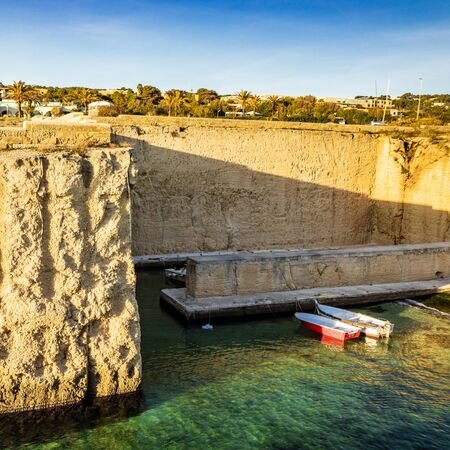 Two small fishing boats moored at the quay of the small port of Porto Miggiano. The port carved into the rock. A limpid, clear turquoise sea. Santa Cesarea Terme, Puglia, Salento, Italy.の写真素材