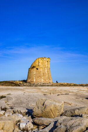 The ancient watch tower of Porto Miggiano, built on the cliffs overlooking the sea. A woman looks at the amazing panorama of the sea. Santa Cesarea Terme, Puglia, Salento, Italy.の写真素材