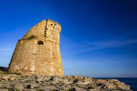 The ancient watch tower of Porto Miggiano, built on the cliffs overlooking the sea. Bleak and rocky landscape with a splendid view of the sea. Santa Cesarea Terme, Puglia, Salento, Italy.の写真素材