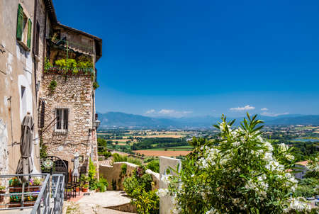 June 30, 2019 - Narni, Umbria, Italy - A glimpse of the ancient village of Narni. A narrow alley. Panorama of the valley and mountains. The blue sky on a summer day.のeditorial素材