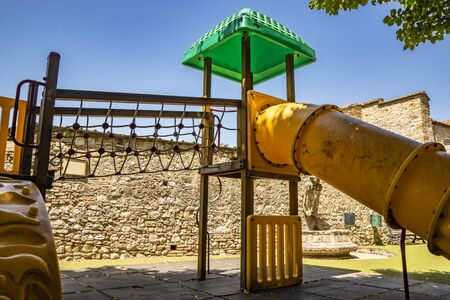 a Tibetan bridge, made of rope, in a playground with a slide and a tube. A game of a public park in Narni, Umbria, Italy.の写真素材