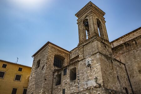Narni, Umbria, Italy - The medieval cathedral of San Giovenaleo in the ancient village of Narni. The side with the bell tower and the church clock. The blue sky in the summer.の写真素材
