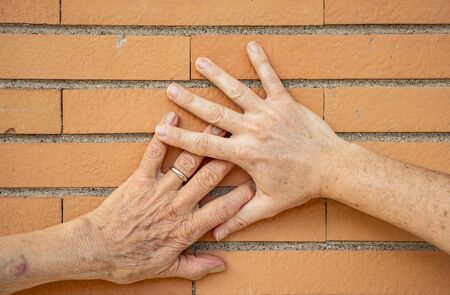 two hands together, grandmother (elderly woman), mother, daughter. Family unity, love, help, assistance. Age and generational difference. United family.の写真素材