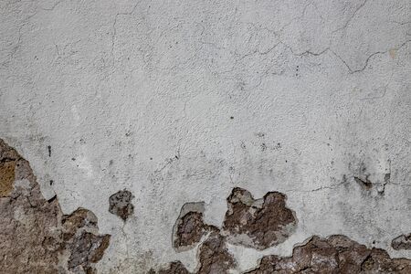 Gray wall ruined by time, bad weather and humidity. Cracks, mold, peeling paint and plaster. Bricks...