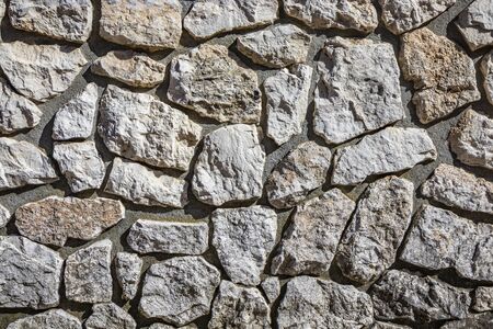 Wall made of cement and irregularly shaped stones. Architectural detail, closeup. Texture, material background.の写真素材