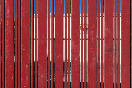Red gate of metal texture. Architectural detail, closeup. Material background. Paint peeling and ruined by time and bad weather.の写真素材