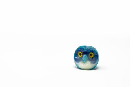 Lucky owl ornament. Small glass lucky object, charm. Blu, azzurro, lilla, viola, giallo. Isolated on white background. Tradition has it that a pair (couple) of owls bring luck.の写真素材