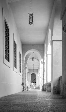 March 24, 2019 - Collepardo, Frosinone, Lazio, Italy - Trisulti Charterhouse. A long corridor under an arcade, with the light passing through the arches and columns. Cross vault.のeditorial素材