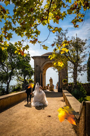 October 14, 2018 - Ravello, Campania, Italy - Two young newlyweds in love, do the photo shoot in Villa Cimbrone, on the Amalfi coast. Just married, in autumn with the leaves falling in the wind.のeditorial素材