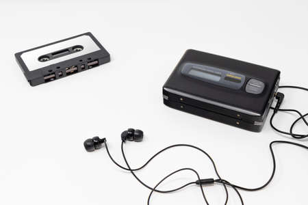 Vintage audio player. Old fashioned portable cassette player, cult object, icon and symbol of the 80s and 90s. Blank audio tape and headphones isolated on white background.の写真素材