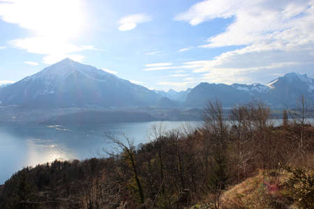 View of the lake, among the snow-capped mountains, in winter. Lake Thun is a lake in the canton of Bern in Switzerland, in the city of Thun. It is a natural lake formed by the river Aare.の写真素材