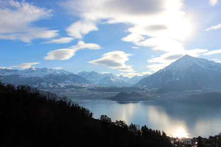 View of the lake, among the snow-capped mountains, in winter. Lake Thun is a lake in the canton of Bern in Switzerland, in the city of Thun. It is a natural lake formed by the river Aare.の写真素材