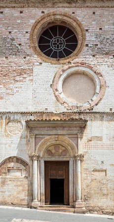 The facade of the church of San Lorenzo, with a loggia from the 12th century, rose windows from the 16th century and decorative elements from the VIII. In Spello, province of Perugia, Umbria, Italy.の写真素材