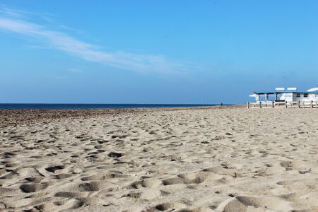 the deserted sea in winter with rough seas, seaweed on the shore and debris on the sand of the beach. A closed bathhouse.の写真素材