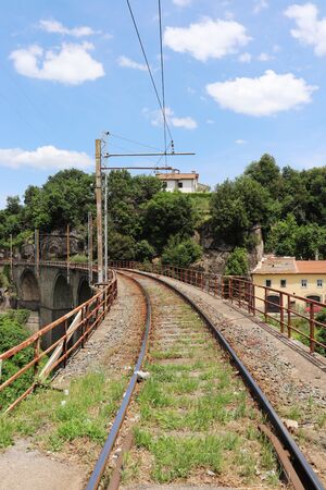 The railroad tracks pass over a stone bridge through a landscape full of vegetation and trees. Elevated rail in perspective. Stone arches.の写真素材