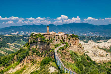 View of the medieval town of Civita di Bagnoregio, located on the top of a spur of tuff rock, in the middle of the valley of the badlands. Connected to the city by a small bridge, mule track.の写真素材