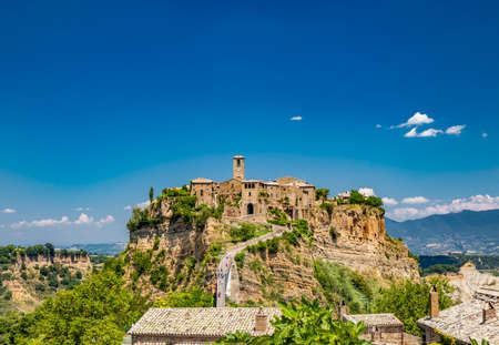 View of the medieval town of Civita di Bagnoregio, located on the top of a spur of tuff rock, in the middle of the valley of the badlands. Connected to the city by a small bridge, mule track.の写真素材