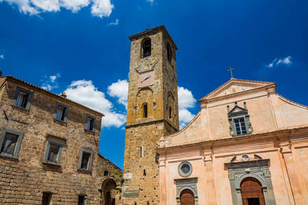 Civita di Bagnoregio, Viterbo, Tuscia, Lazio, Italy. The Church of San Donato with the bell tower and the clock. Three wooden doors.の写真素材